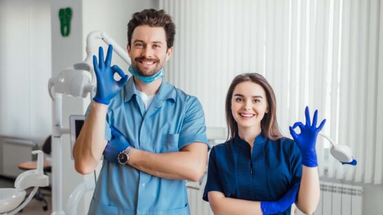 photo smiling dentist standing with arms crossed with her colleague showing okay sign